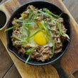 Load image into Gallery viewer, Duck Sisig — pulled duck served in cast iron skillet with egg and spring onions

